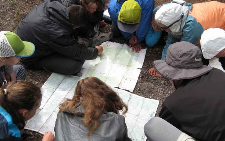 a group of outward bound students examine a map on a backpacking expedition in oregon